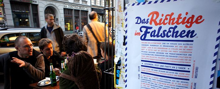 Plakat Das Richtige im Falschen neben Gästen vor einem Berliner Café