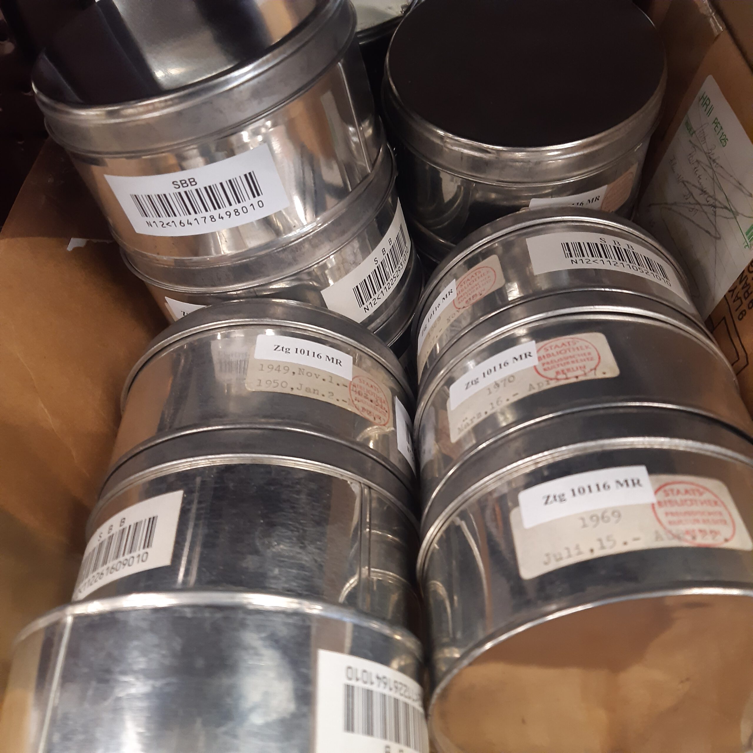 Mikrofilmrollen in beschrifteten Metallbehältern
